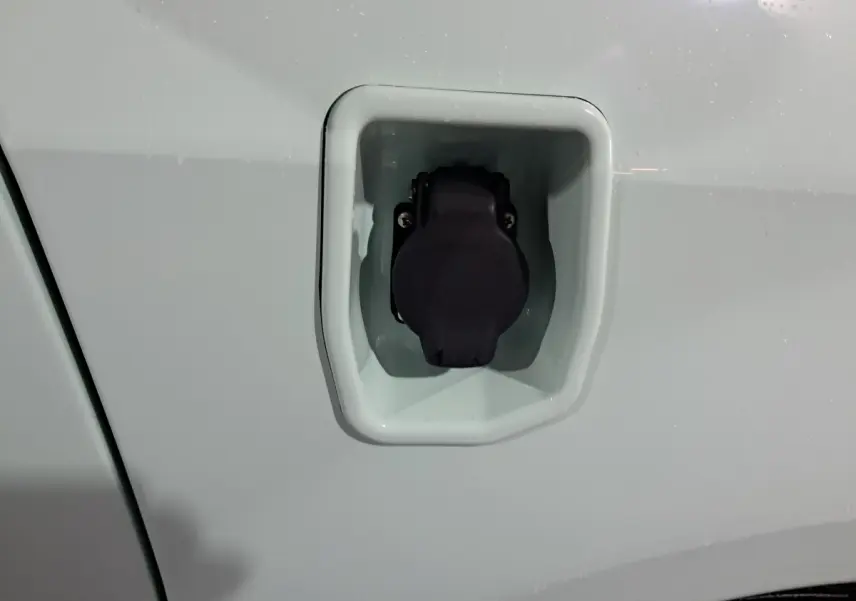 Prise de recharge électrique en gros plan sur la carrosserie verte côté conducteur de l'AIXAM MINAUTO E chic 2026.