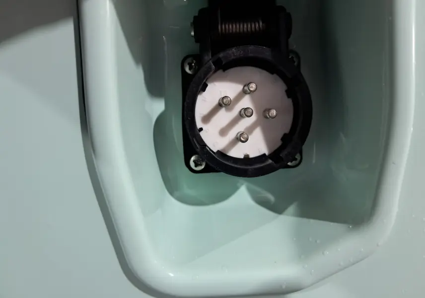 Gros plan sur la prise de recharge électrique intégrée dans la carrosserie verte de l'AIXAM MINAUTO E chic 2026.