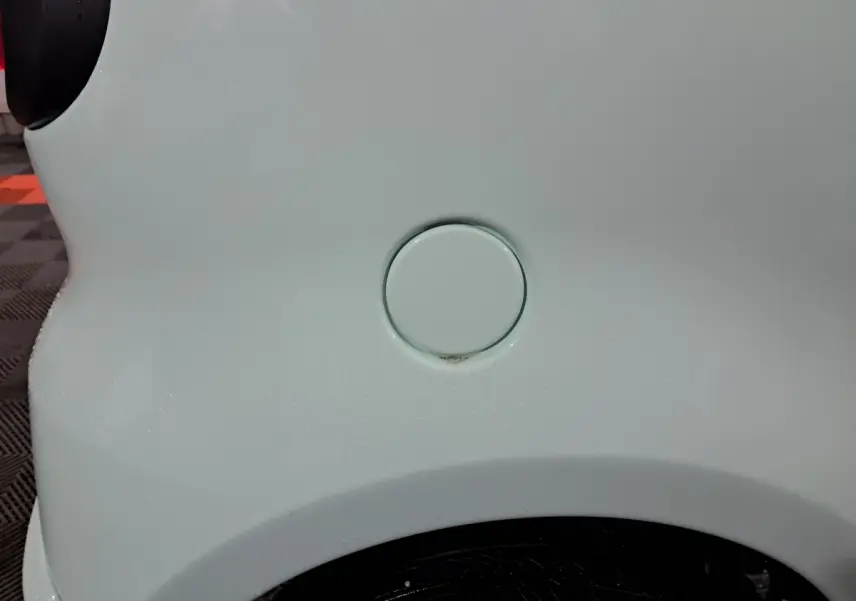 Gros plan sur la trappe de recharge côté gauche d'une Aixam Minauto E chic 2026 verte électrique.