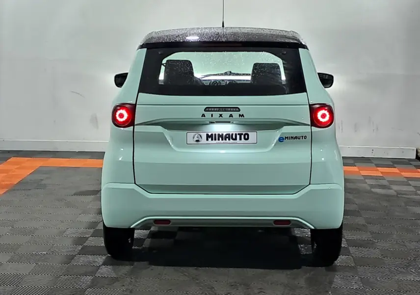 Vue arrière d'une AIXAM MINAUTO E chic 2026 électrique vert clair avec feux ronds allumés et toit noir.