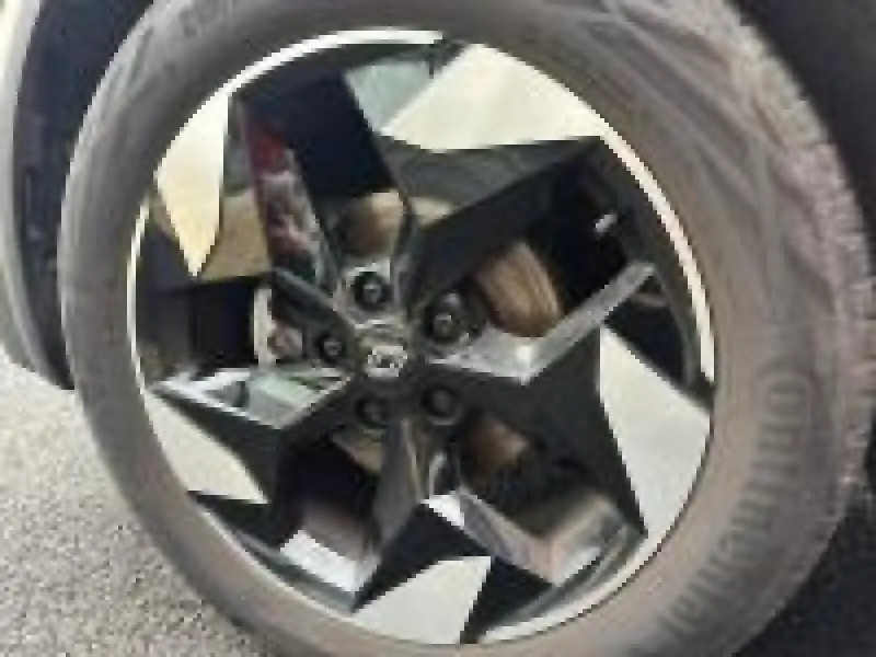 Gros plan sur la jante alliage noire et argentée du Renault Captur 2025 Rouge Flamme, mettant en valeur son design moderne.