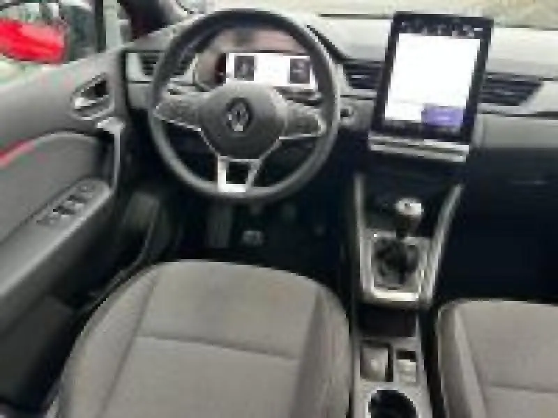 Vue intérieure avant du Renault Captur rouge 2025, volant multifonction, écran tactile vertical et boîte manuelle.