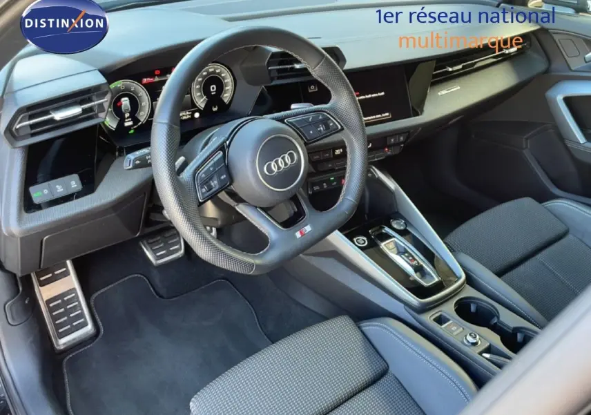 Vue intérieure côté conducteur de l'Audi A3 Sportback 40 TFSIe 2025, volant sport, tableau de bord digital et sellerie tissu noir.