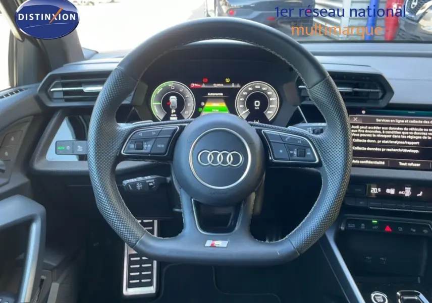 Vue intérieure centrée sur le volant sport perforé noir de l'Audi A3 Sportback 40 TFSIe 2025 avec tableau de bord digital.