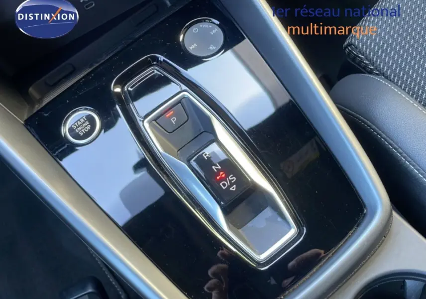 Gros plan sur la console centrale noire brillante de l'Audi A3 Sportback 40 TFSIe avec sélecteur de boîte auto et bouton start/stop.