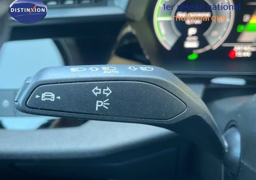 Gros plan sur la commande de clignotants et feux d'Audi A3 Sportback 40 TFSIe noire, tableau de bord numérique en arrière-plan.