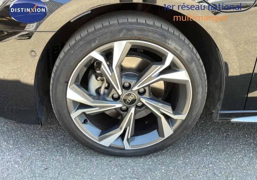 Gros plan sur la roue avant droite d’une Audi A3 Sportback noire, mettant en valeur la jante en alliage au design moderne.