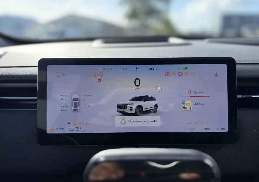 Écran digital du tableau de bord affichant la JAECOO J7 PHEV blanc khaki en vue 3/4 avant avec informations de conduite.