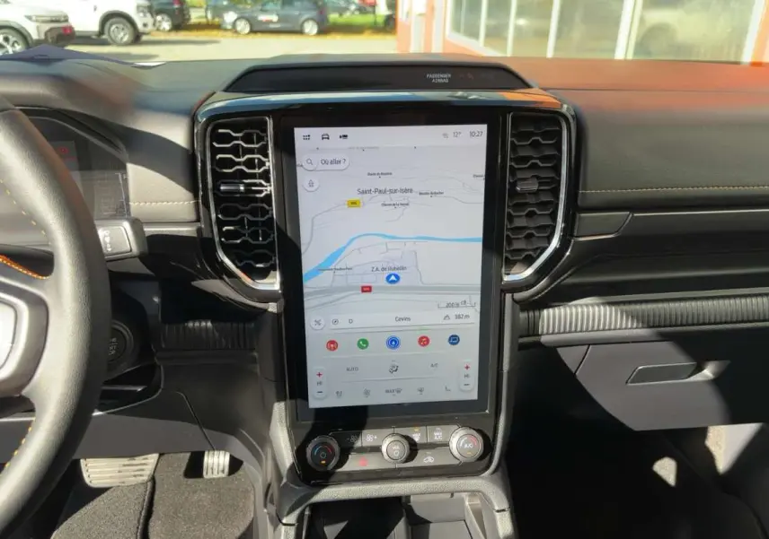 Vue intérieure centrée sur l’écran tactile vertical du Ford Ranger gris carbone avec tableau de bord noir et volant partiel.