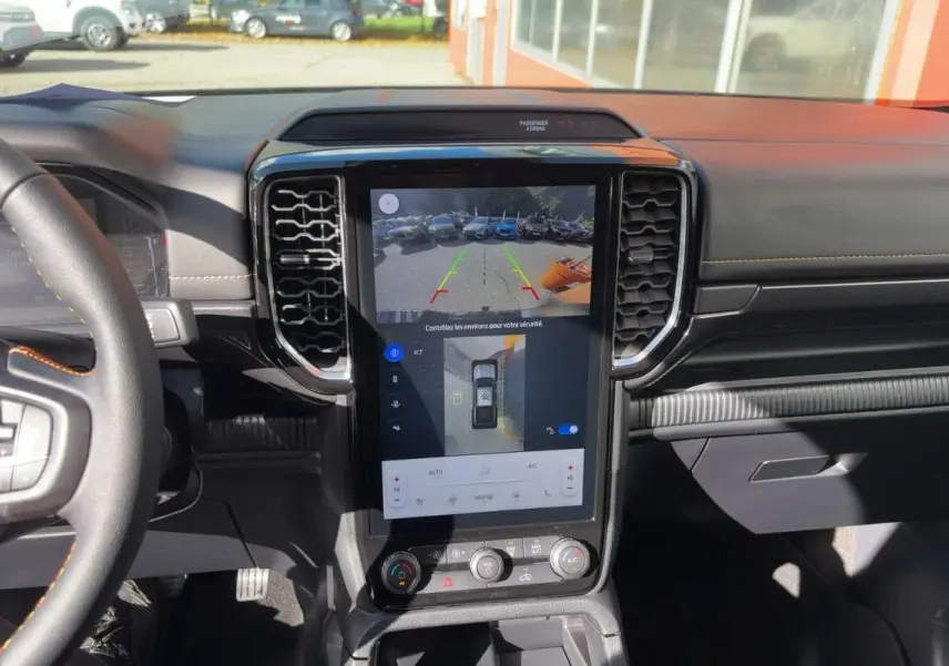 Vue intérieure du tableau de bord du Ford Ranger gris carbone 2026, avec écran tactile central affichant la caméra 360° et aides au stationnement.