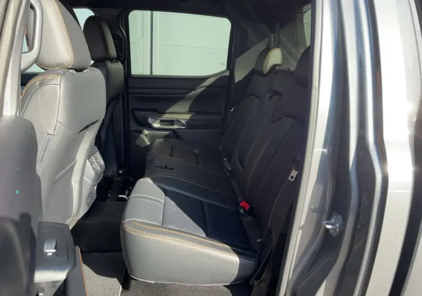 Vue intérieure côté droit des sièges arrière en cuir noir avec surpiqûres orange du Ford Ranger gris carbone 2026.