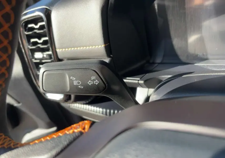 Gros plan sur la commande de clignotants à gauche du volant cuir noir avec surpiqûres orange du Ford Ranger gris carbone.