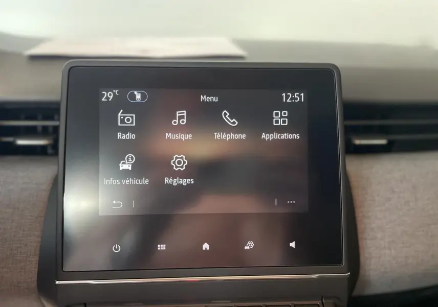 Écran tactile central de la Renault Clio 2025 avec menu principal et aérateurs latéraux chrome satiné visibles.