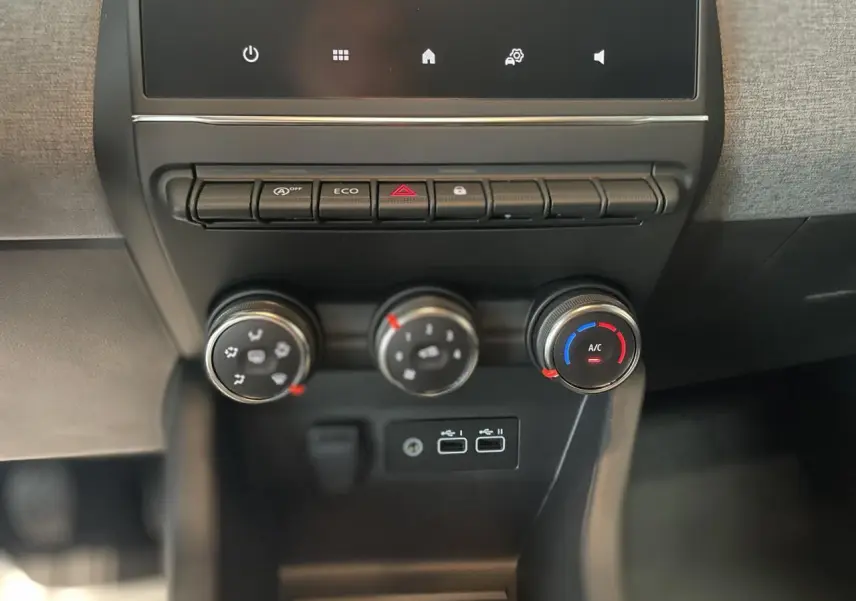 Gros plan sur la console centrale de la Renault Clio 2025 avec commandes de climatisation et ports USB visibles.
