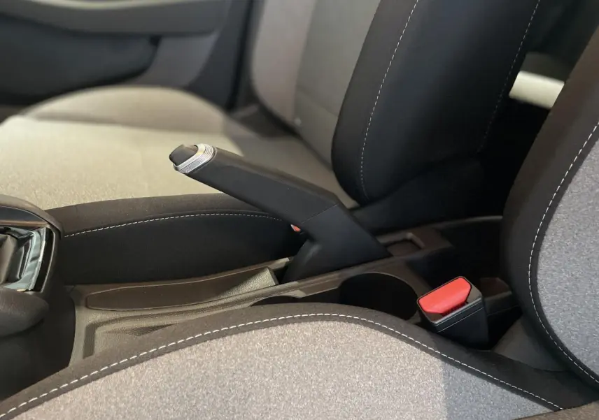 Gros plan sur le frein à main manuel et la sellerie tissu gris avec surpiqûres blanches de la Renault Clio 2025.