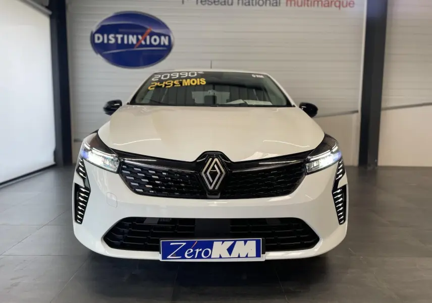 Vue frontale d'une Renault Clio blanche 2025 avec calandre noire et feux LED allumés en showroom.