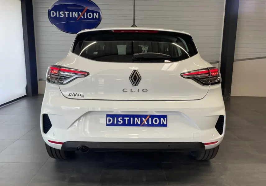 Vue arrière d'une Renault Clio blanche 2025 avec feux LED et logo distinctif dans un showroom.