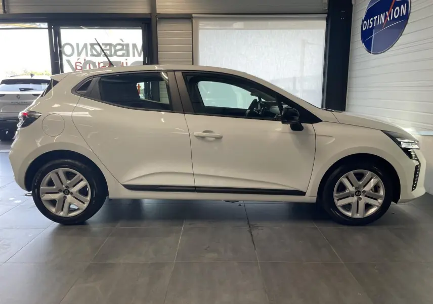 Profil droit d'une Renault Clio blanche 2025 avec jantes alliage et poignées couleur carrosserie en showroom.