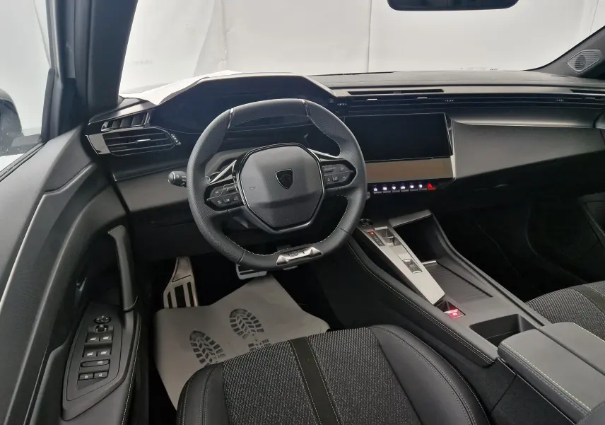 Vue intérieure du poste de conduite de la Peugeot 308 2025, avec volant compact, écran tactile et sellerie noire moderne.