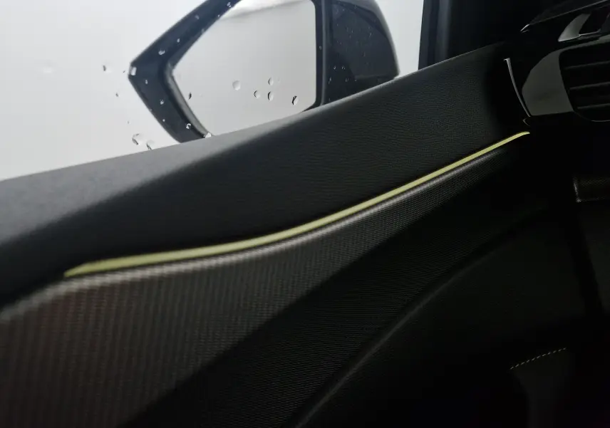 Détail de la porte côté gauche d'une Peugeot 308 2025 blanche, avec insert décoratif et éclairage d'ambiance subtil.