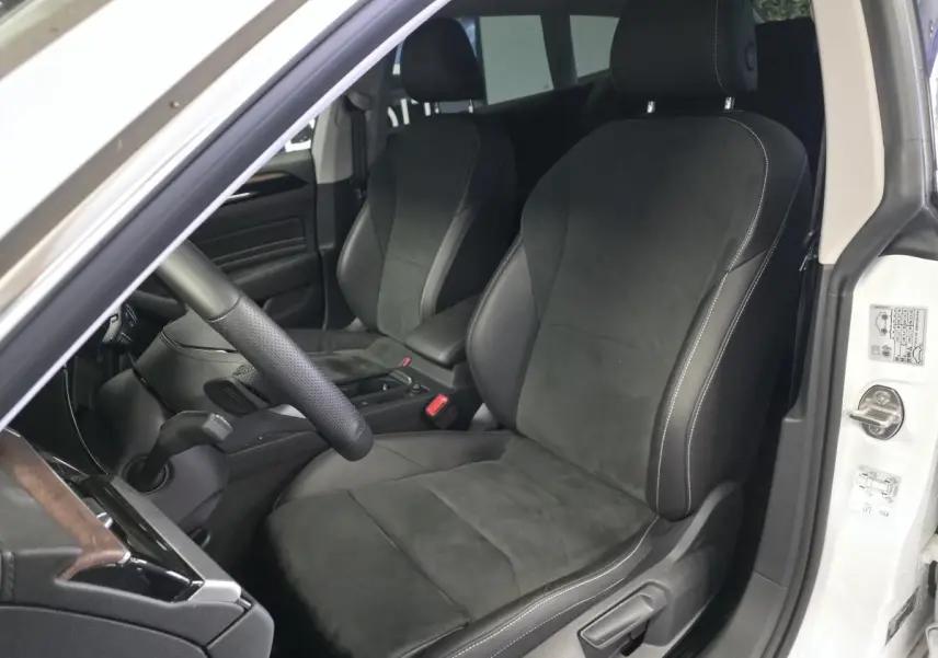 Vue intérieure côté conducteur de la Volkswagen Arteon Elegance blanche avec sièges avant en microfibre noire et coutures contrastées.