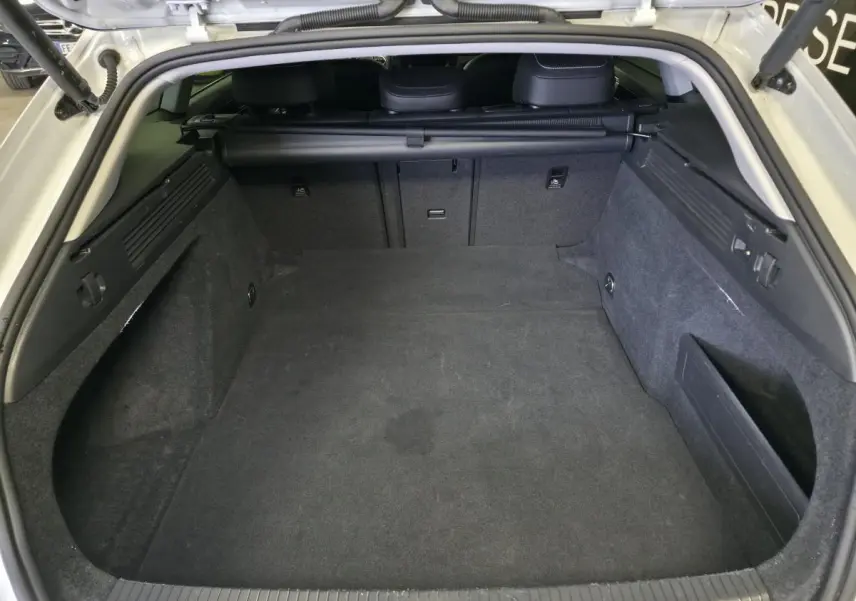 Coffre ouvert vu de l'arrière d'une Volkswagen Arteon Shooting Brake blanche, intérieur spacieux et tapis gris foncé.