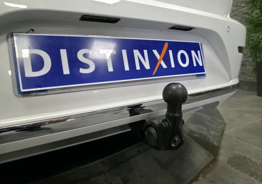 Gros plan sur l'attelage rabattable noir à l'arrière d'une Volkswagen Arteon blanche avec plaque Distinxion.