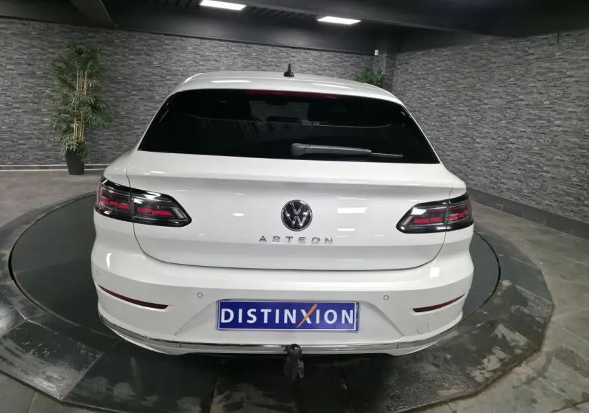 Vue arrière d'une Volkswagen Arteon blanche avec feux LED sombres et attelage rabattable électrique visible.
