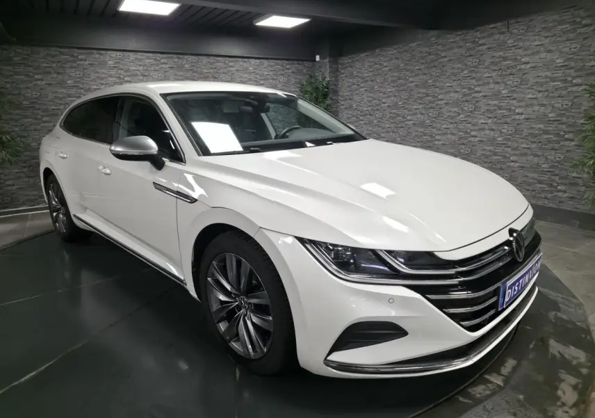 Volkswagen Arteon blanc nacré vu en 3/4 avant droit, avec calandre chromée et jantes alliage 18 pouces.