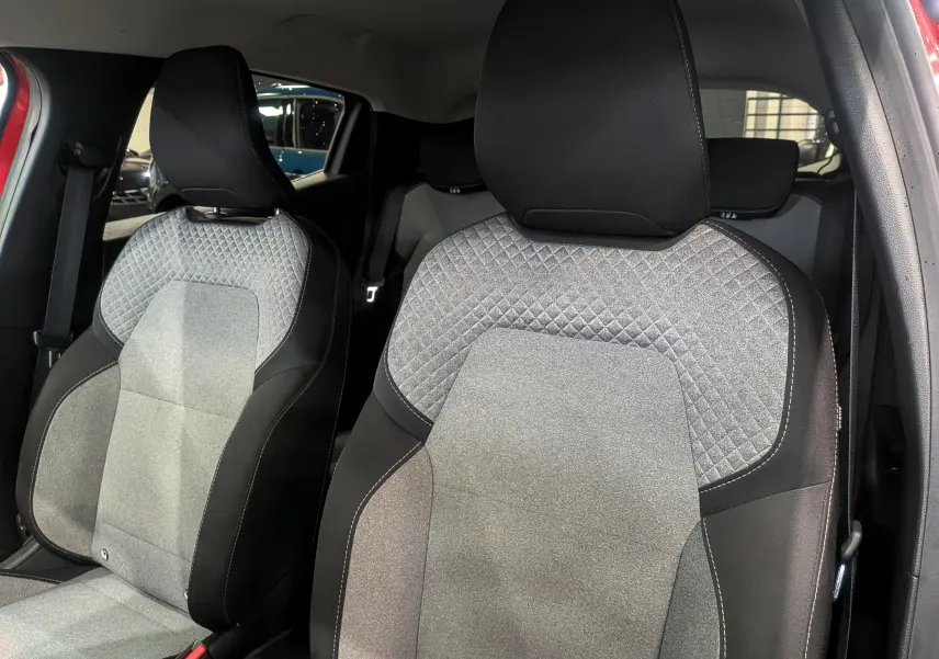 Gros plan sur les sièges avant gris et noirs de la Renault Clio V Rouge Flamme, mettant en valeur leur tissu matelassé.