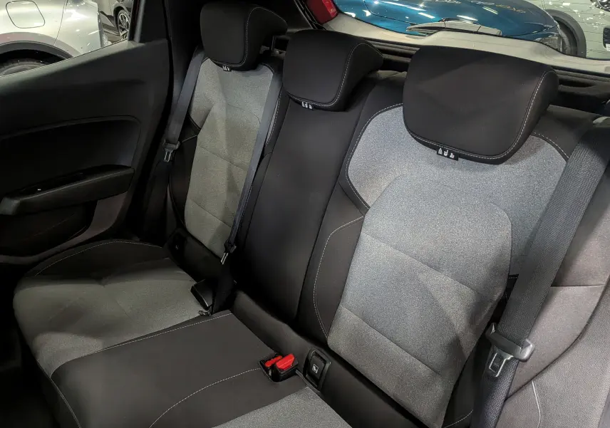 Vue intérieure des sièges arrière en tissu gris et noir de la Renault Clio V Rouge Flamme, avec ceintures de sécurité visibles.