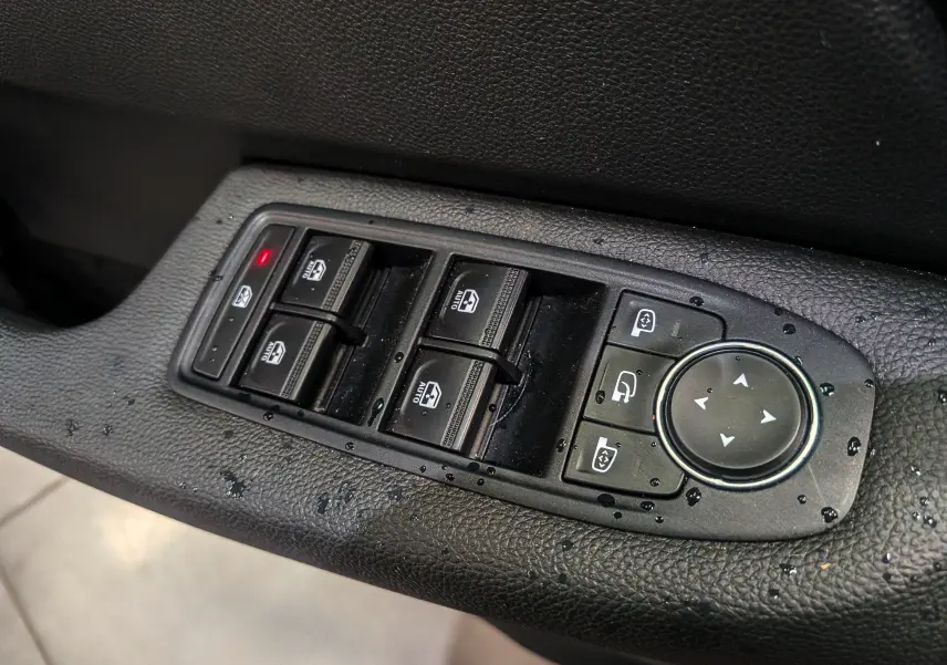 Gros plan sur les commandes des vitres et rétroviseurs électriques sur la porte côté gauche d'une Renault Clio V.