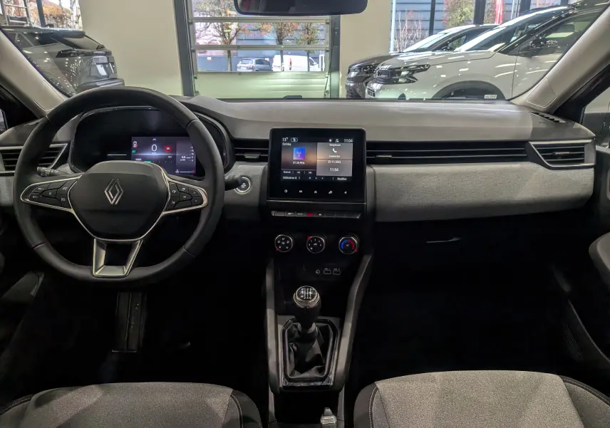 Intérieur de la Renault Clio V rouge Flamme, vue frontale du tableau de bord avec volant, écran tactile et boîte manuelle.