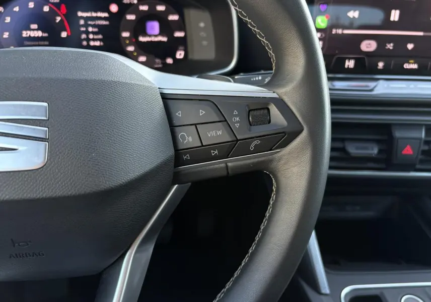 Gros plan sur le volant cuir multifonction à droite du SEAT Leon 2025, avec affichage digital et commandes intégrées.