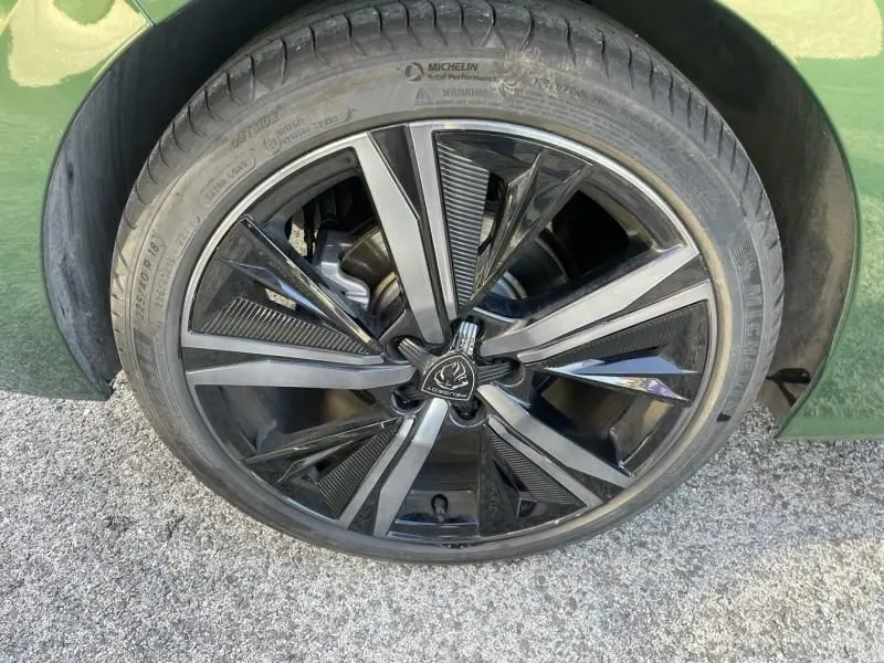 Gros plan sur la roue avant gauche d'une Peugeot 308 1.5 HDI 130 GT PACK 2022 en vert olivine avec jante alliage noire et argent.