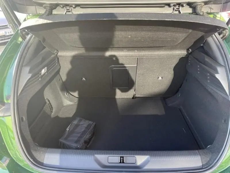 Coffre ouvert vu de l'arrière d'une Peugeot 308 1.5 HDI 130 GT PACK vert olivine, montrant un espace de rangement vide avec un petit sac noir.