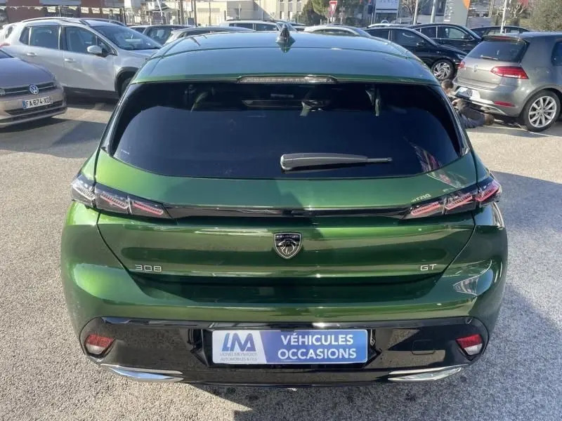 Vue arrière d'une Peugeot 308 GT vert olivine 2022, soulignant ses feux LED et son logo lion central.