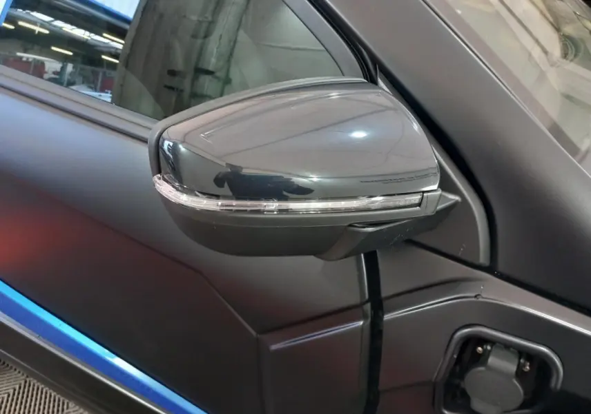 Gros plan sur le rétroviseur côté conducteur noir avec clignotant, sur la portière bleue de l’AIXAM MEGA électrique 2026.