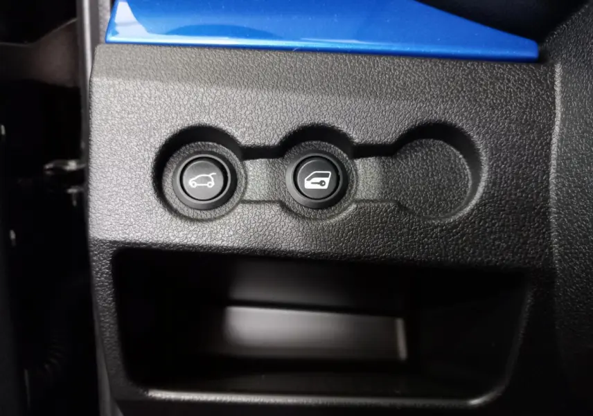 Gros plan sur les boutons d’ouverture du coffre et de la trappe à carburant dans l’habitacle d’une Aixam Mega bleu.