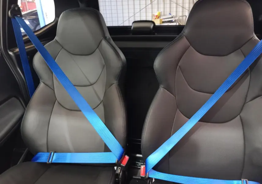 Vue intérieure rapprochée des sièges avant noirs avec ceintures de sécurité bleues dans l'AIXAM MEGA E-SCOUTY EVO 2026.