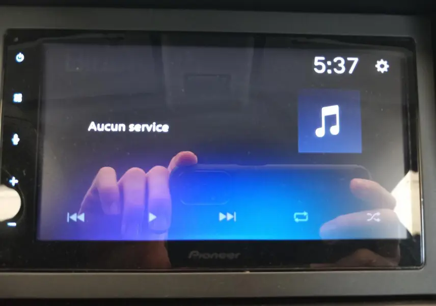 Écran tactile Pioneer du tableau de bord avec affichage musical et reflet des mains en gros plan.