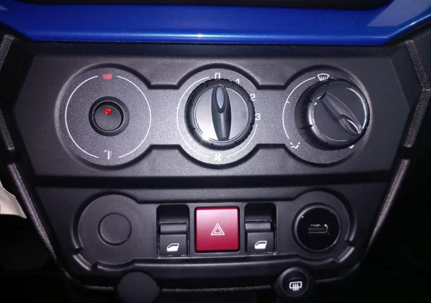 Gros plan sur la console centrale noire de l'AIXAM MEGA E-SCOUTY EVO bleu, montrant les commandes de climatisation et boutons.