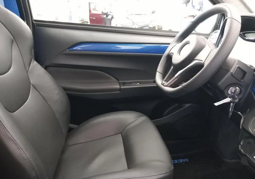 Vue intérieure côté conducteur de l'AIXAM MEGA E-SCOUTY EVO 2026 avec garniture bleue et sièges noirs en cuir.