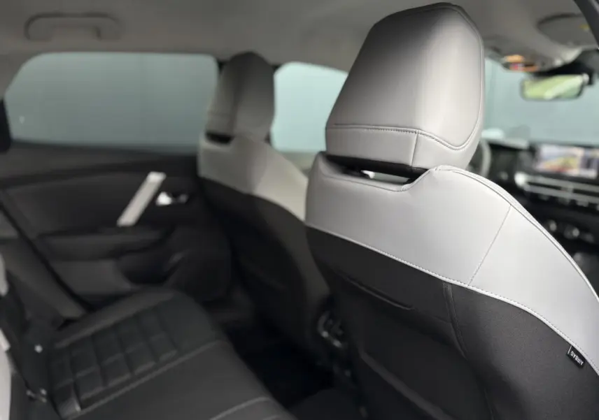 Vue intérieure arrière côté gauche des sièges bicolores gris clair et noir de la Citroën C4 Hybrid 2025.