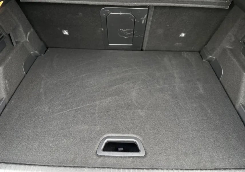 Coffre spacieux vu de dessus, revêtement gris foncé avec trappe d’accès au fond sur Citroën C4 Hybrid 2025.