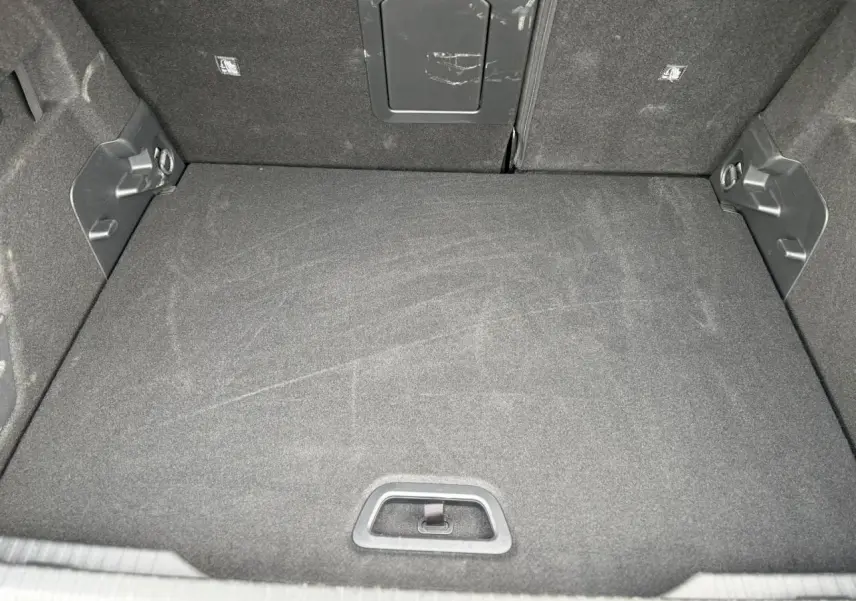 Coffre spacieux vu de face, revêtement tissu noir, avec trappe d'accès et fixations latérales visibles.