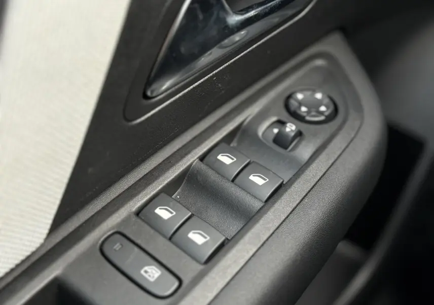 Gros plan sur les commandes de lève-vitres et rétroviseurs côté conducteur d'une Citroën C4 Hybrid 145 gris Mercury.