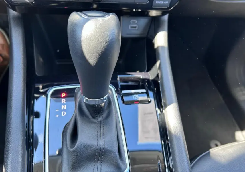 Gros plan sur la commande de la boîte automatique noire et cuir dans l’habitacle du Jeep Compass gris 2024.