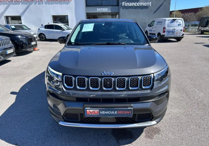 Vue avant d’un Jeep Compass gris 2024 avec calandre chromée et phares LED distinctifs, stationné en extérieur.