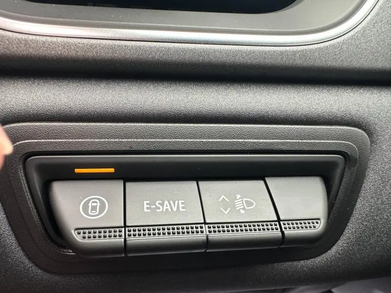 Gros plan sur les boutons de commande du tableau de bord du Renault Captur rouge, avec fonction E-SAVE activée.